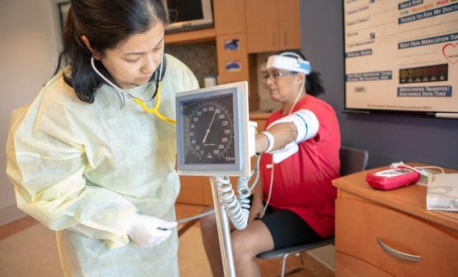 En una oficina médica, una persona mide la presión arterial de otra. 