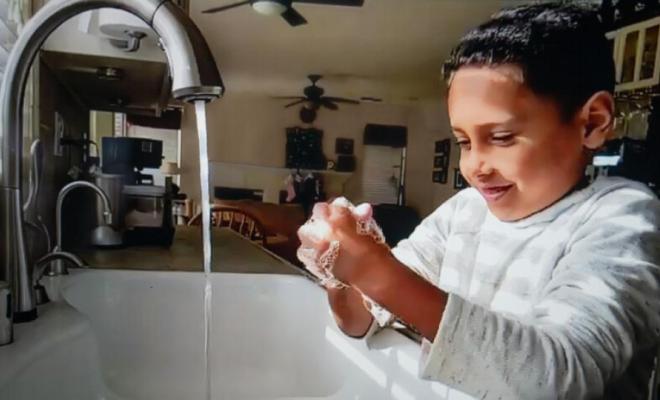 Un niño con pelo negro se lava las manos