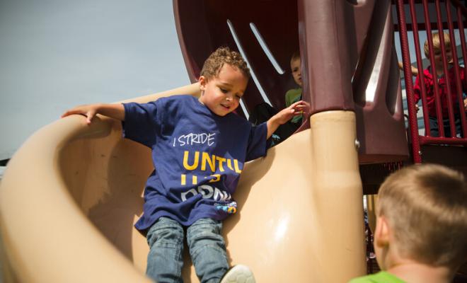 Un niño pequeño se desliza por un tobogán en un parque