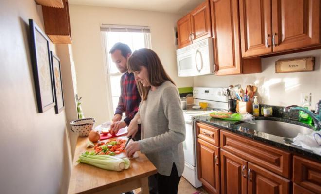 En una cocina, dos adultos cortan vegetales